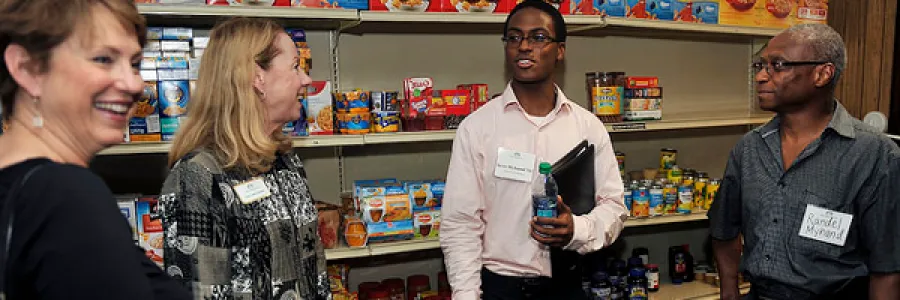 Group of individuals standing in front of shelves of pantry items.